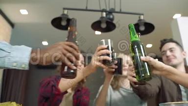 一群朋友在聚会上举起瓶子和叮当作响的眼镜。 青年和假日的概念
