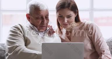 微笑着年轻的成年孙女用笔记本电脑教老爷爷