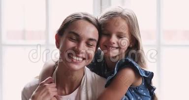漂亮的笑脸女儿拥抱妈妈看镜头