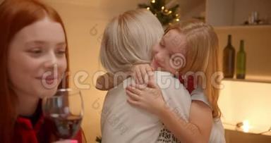 一个金发小女孩在圣诞礼物晚宴上拥抱祖父母