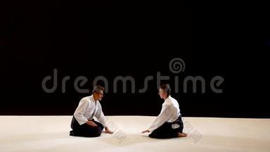 两个大师<strong>武术</strong>合气道互相鞠躬。 拍摄在黑白<strong>背景</strong>上。 慢动作。