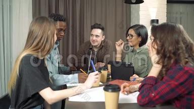 在现代办公室会见创意商业团队。 多种族的年轻人讨论创业想法。