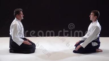 两个大师武术合气道互相鞠躬。 拍摄在黑白背景上。 慢动作。 快关门。