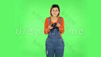 女孩玩电子游戏使用无线控制器与喜悦和失败。 绿色屏幕