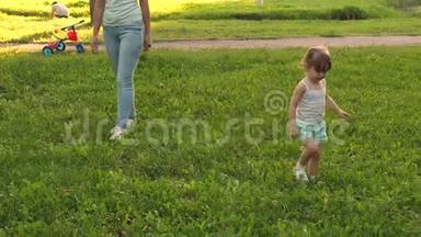 小女儿和<strong>妈妈</strong>在草坪上公园散步。 孩子走在绿草上。 <strong>妈妈</strong>和<strong>宝宝</strong>在草坪上休息.. 一种概念