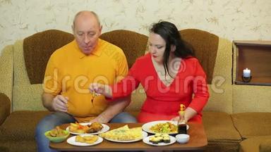 一男一女一家人在一个有炸鸡和蔬菜的房间里吃晚饭。
