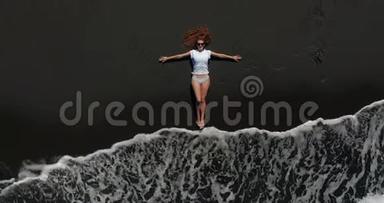 空中观景。 美丽的女人躺在特内里费的<strong>黑色</strong>海滩上休息，而一个漫长的海洋浪<strong>潮</strong>即将到来。