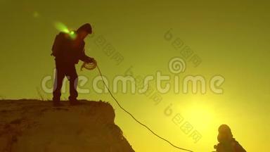 登山者用绳子爬山. 女旅行者摔下悬崖。 游客的团队合作。 旅费