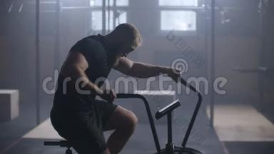 年轻的活跃男子在健身房<strong>旋转空气</strong>自行车。 男子慢动作的空中自行车训练。 中型健身男子工作