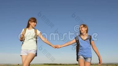 女游客牵着手去。 免费的女孩旅行者带着背包在农村旅行。 团队合作游客