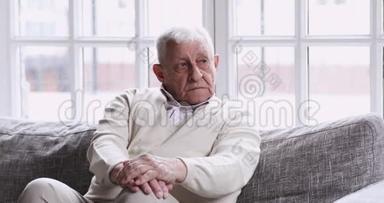 孤独的老爷爷独自坐在沙发上看着