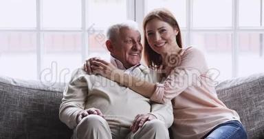 幸福的小孙女抱着老爷爷坐在沙发上，画像