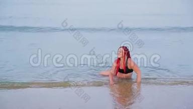一个穿着红色辫子的黑色泳衣的女人坐在海里，从迎面而来的海浪中坠落