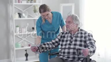 职业护士穿着蓝色制服和眼镜，帮助老年残疾人在养老院锻炼。 无效<strong>投标</strong>