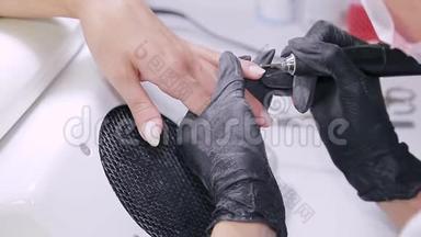 美容店里戴手套的医生处理病人指甲上的角质层