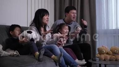 亚洲家庭在家庭房间里看足球比赛