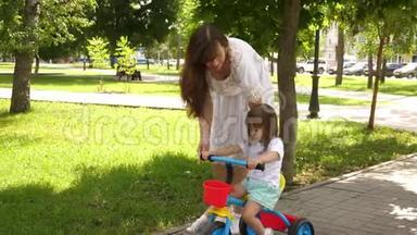 孩子学会骑自行车。 幸福家庭和童年的概念。 父母和小女儿在公园散步。 快乐