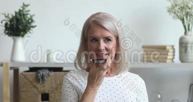 微笑的老太太在手机上激活虚拟数字语音助手