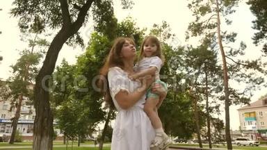 快乐的童年概念。 快乐的妈妈在户外公园拥抱小女儿。 漂亮的妈妈和她的宝宝在玩