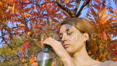 美丽的女孩正在公园里的一棵树上喝绿饮料、螺旋藻、<strong>小球藻</strong>和麦草冰沙