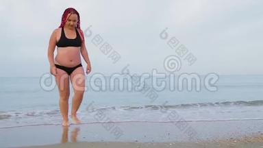 一个穿着黑色泳衣的女人从海<strong>上上</strong>岸。