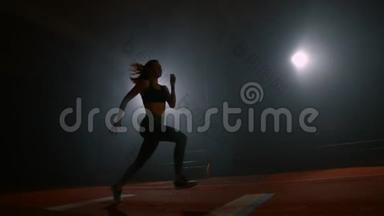 一名运动女子在<strong>体育场</strong>内奔跑，在黑暗的背景下在<strong>体育场</strong>内缓慢地进行跳远运动