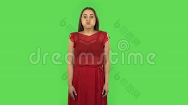 穿着红色裙子的温柔<strong>女孩正</strong>在为相机摆姿势，做滑稽的<strong>脸</strong>。 绿色屏幕