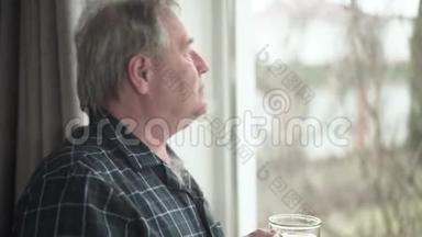 侧面的肖像，体贴的高加索人，看着窗外，在室内喝茶。 孤独男