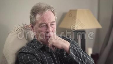 愁绪不宁的白种人老人坐在家里思考的画像.. 相机接近退休人员的消费日