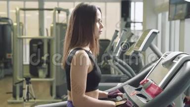 健身妇女在健身房跑步机上做有氧训练。 健身中心的运动女孩使用跑步机