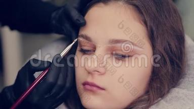 在一家美容院，专业的眉毛师女士给客户<strong>画眉</strong>毛。