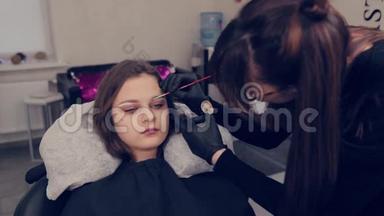 专业的眉毛大师在美容院用刷子给客户<strong>画眉</strong>毛。