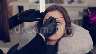 专业的眉毛大师在美容院用刷子给客户<strong>画眉</strong>毛。