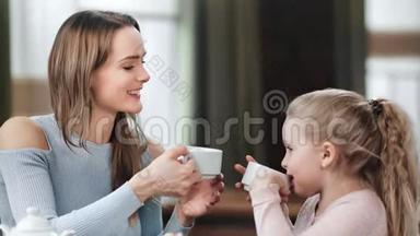 美丽的年轻妈妈和可爱的女儿聊天喝茶。 中型近距离拍摄4k红<strong>色相</strong>机