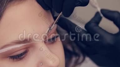 专业的眉毛大师在美容院用刷子给客户画眉毛。
