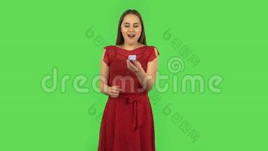 穿红色衣服的温柔女孩正打开一个小盒子，带着<strong>惊喜</strong>，非常高兴，说是的。 绿色屏幕