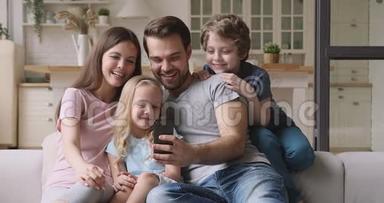 使用智能手机，在舒适的沙发上放松快乐的亲密家庭。