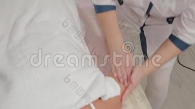 女按摩师在按摩院给一个小女孩整只胳膊做按摩。