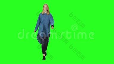 一个金发少女在绿幕背景下微笑着跑向会场。彩色键，4k镜头。正视图。