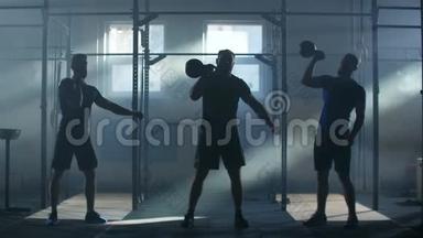 慢速运动：三名运动员在一个大气健身室中，在阳光的背景下举重