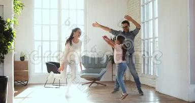 活泼无忧无虑的父母和小女儿在家里一起跳舞