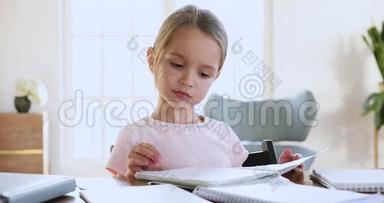 可爱的女学生拿着<strong>作业本</strong>检查作业坐在书桌上