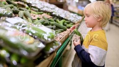可爱的小男孩选择新鲜的有机黄瓜，并放入网状购物袋在食品商店或超市。 <strong>零废物</strong>概念