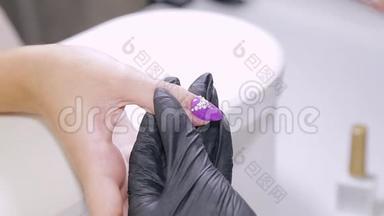美容院的美甲师给顾客的指甲涂上带水钻的凝胶清漆