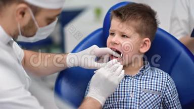 在牙医检查牙齿时，坐在扶手椅上的男孩子。 4K红色相机拍摄