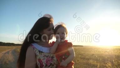 快乐的妈妈抱着孩子散步。 妈妈和小女儿正走在麦田里的<strong>乡间小路</strong>上