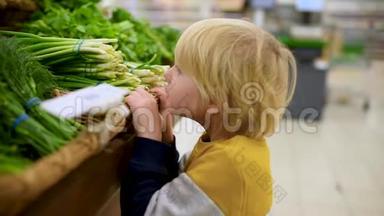 <strong>可爱</strong>的小男孩在食品商店或<strong>超</strong>市选择新鲜的有机绿色：洋葱，欧芹，鳃，生菜，沙拉，茴香，韭菜。