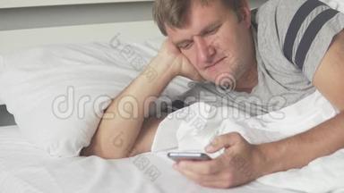 一个拿着手机的男人早上躺在床上检查
