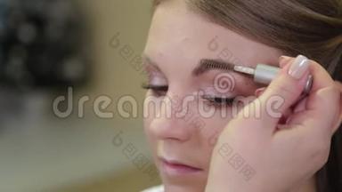 专业化妆师用特殊的画笔向客户画眉毛。