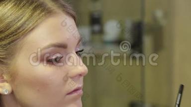专业化妆师用特殊的画笔向客户画眉毛。